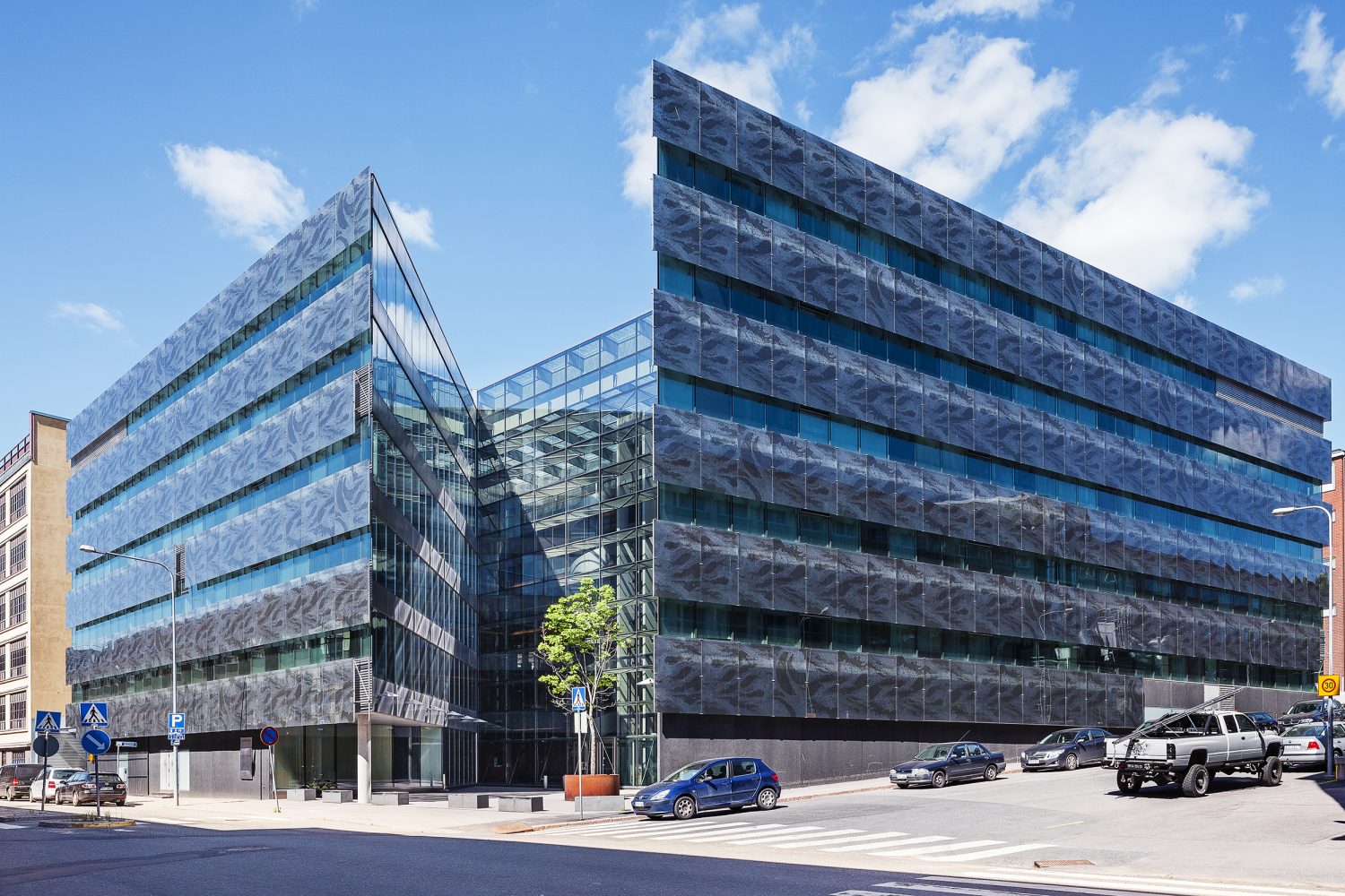 Glass office building, street and cars in front.